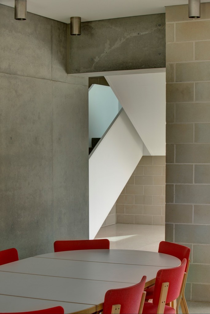 Block House house: Artek dining table and chairs in bright red contrast well with the grey and white background.