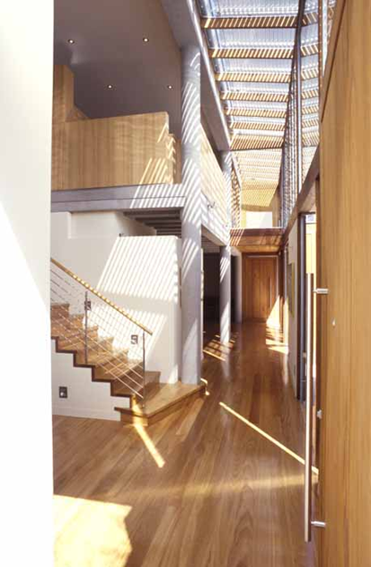 Woollahra house: The neighbouring void space with timber floors and joinery, flooded with natural light adjustable with external louvres.