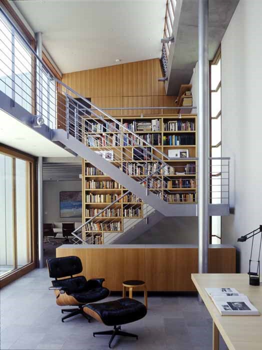 Woollahra house: the void space over a study/dining area with limestone floor tiles, off-form concrete, blackbutt veneer joinery and an eames lounge chair, Artek stool and Tizio lamp